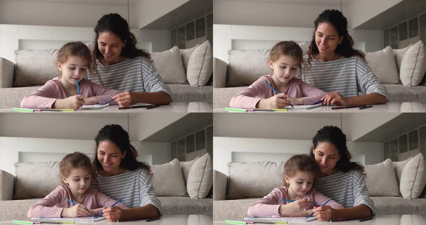 小孩子女儿和有爱心的母亲在纸质相册里画画。