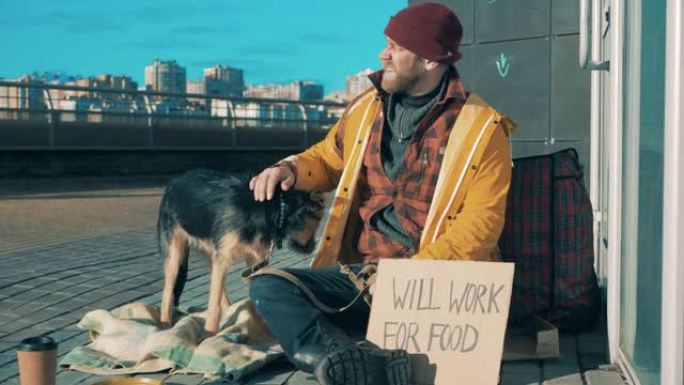城市街道上有一个可怜的人和他的狗坐在地上