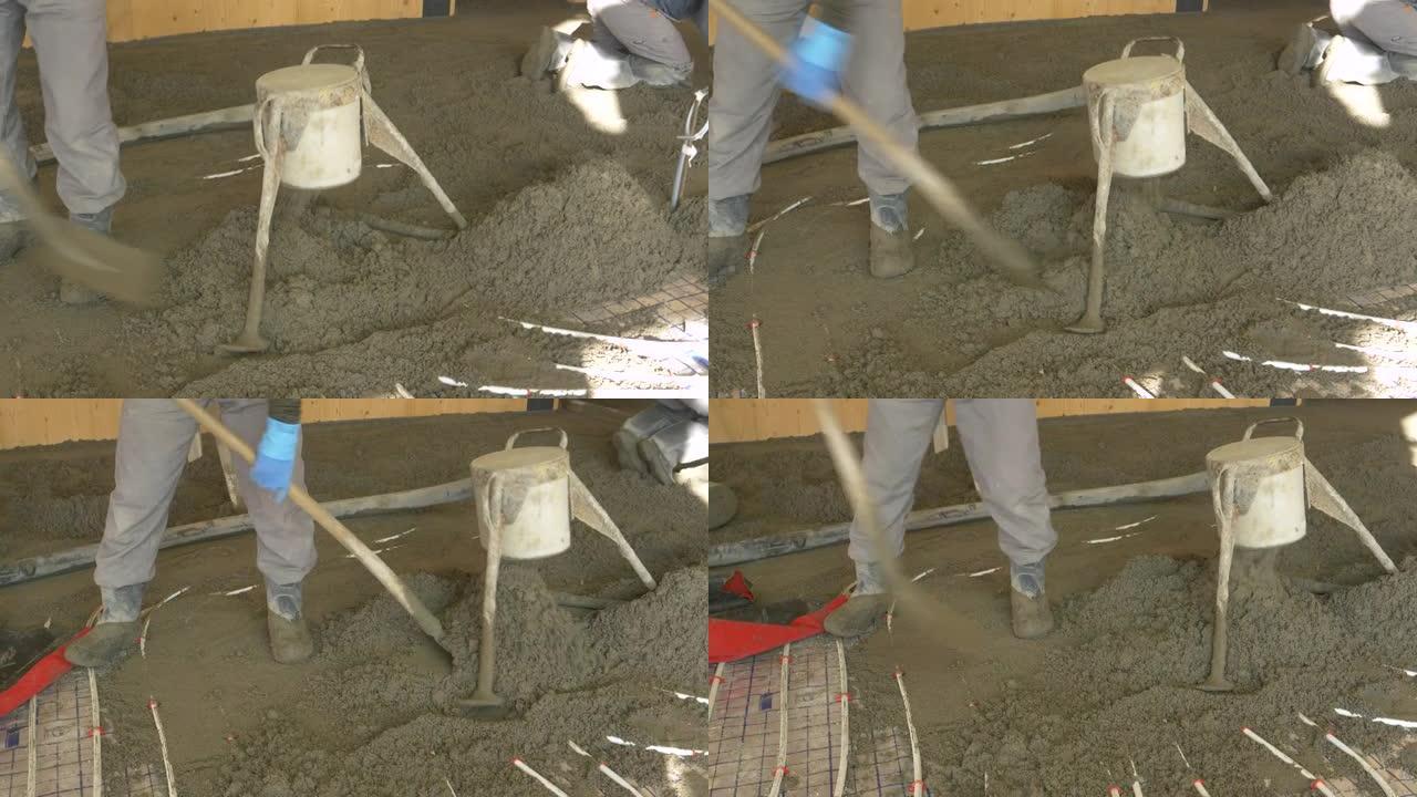 特写: 工人将湿水泥撒在未完工房屋的地面上。