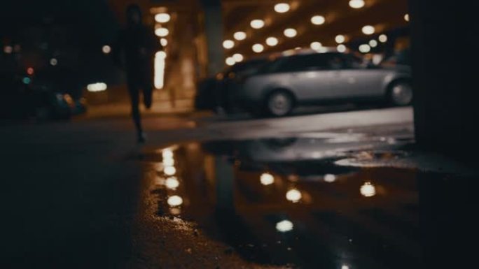 SLO MO慢跑者晚上在城市慢跑时走进水坑