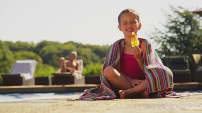 暑假与女孩在游泳池边缘吃冰棍的家庭