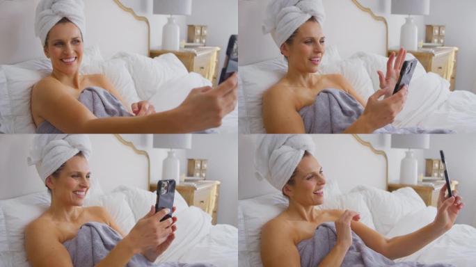 熟女躺在床上穿毛巾在家手机自拍笑