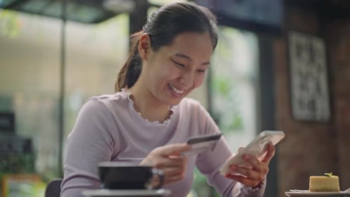 年轻的亚洲妇女用信用卡从手机上订购在线购物