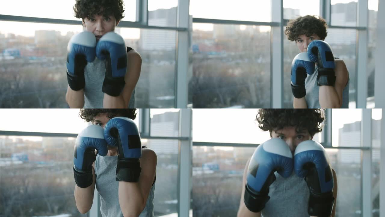 有动力的女拳击手戴着手套看着相机，在健身房跳拳