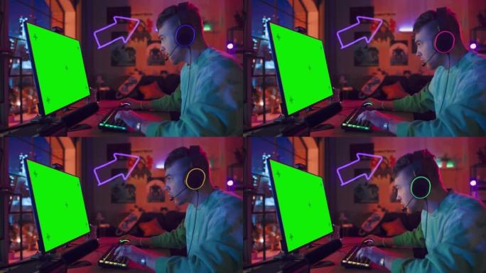 兴奋的玩家玩在线视频游戏，在他功能强大的个人电脑上模拟绿屏。房间和电脑有彩色霓虹灯。阁楼公寓舒适的夜
