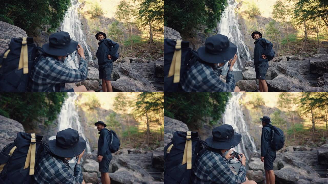 亚洲徒步旅行者在瀑布上摆姿势拍照，供朋友拍照