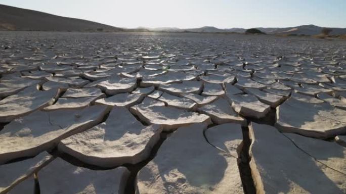 气候变化。由于气候变化和全球变暖造成的干旱，干旱大坝的图案化开裂的泥浆表面的平移特写视图