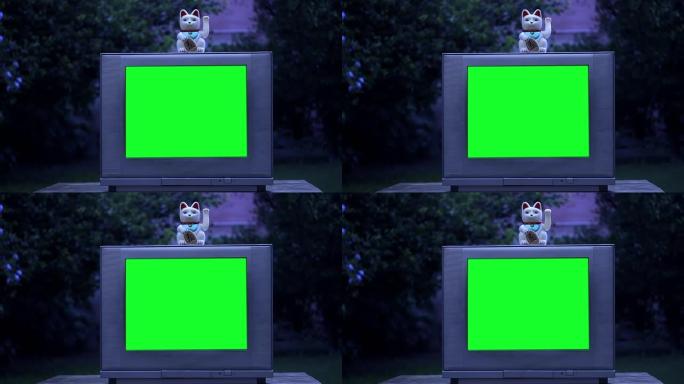 Maneki Neko猫和绿屏旧电视。夜色。