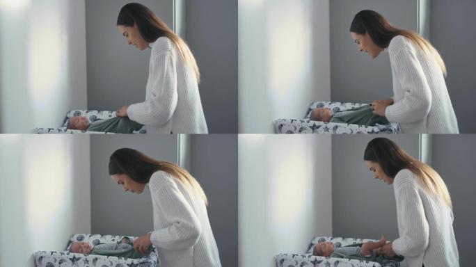 4k视频片段，一名妇女在换衣桌上脱下婴儿的衣服