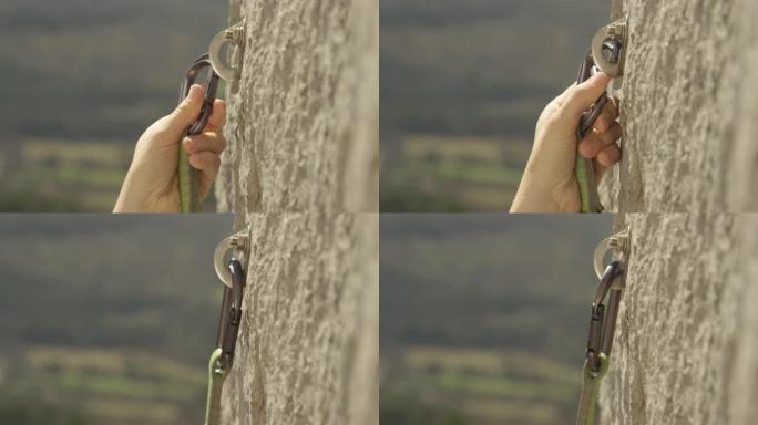特写: 攀岩者将登山扣夹在拧入悬崖的螺栓中。