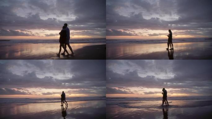 深情的夫妇在黄昏时在海滩上散步