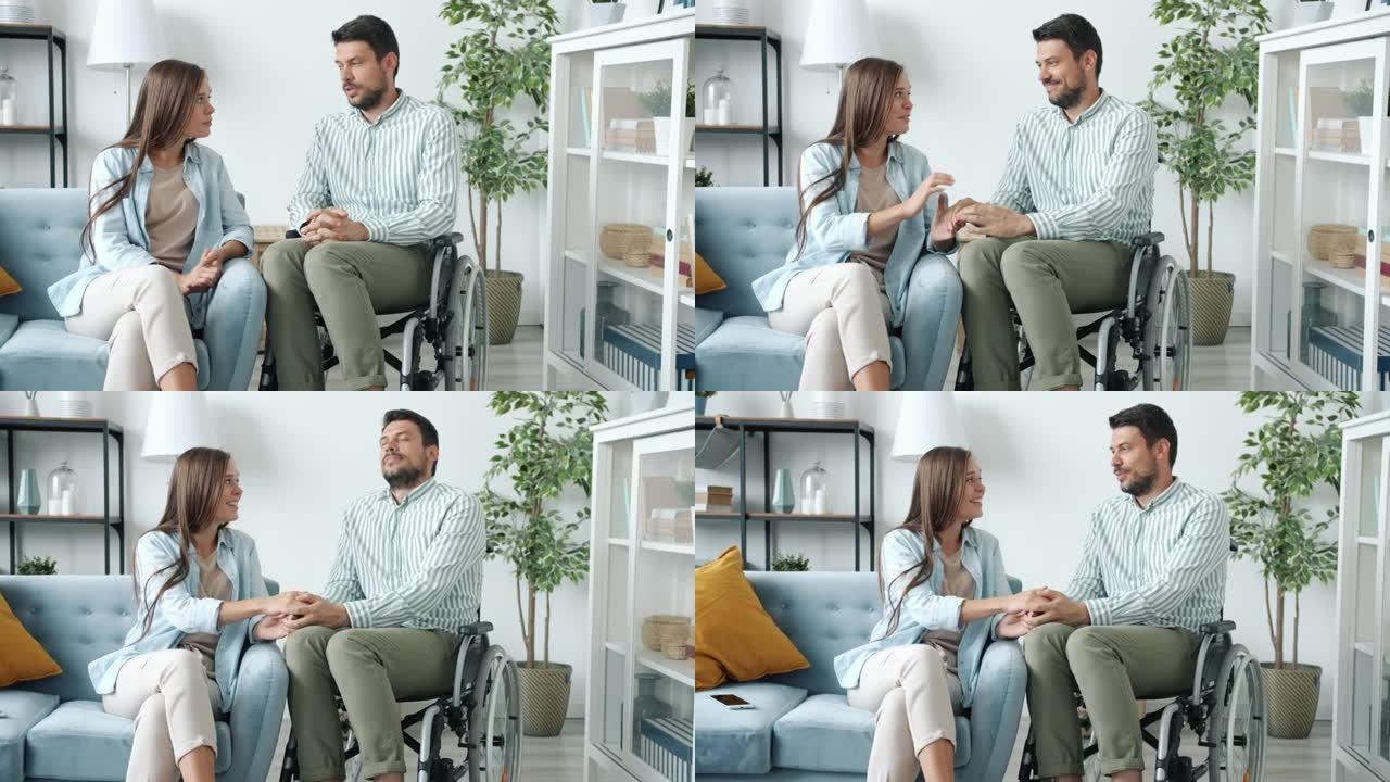 坐在轮椅上的残疾男子在家里与微笑着牵手的女人交谈