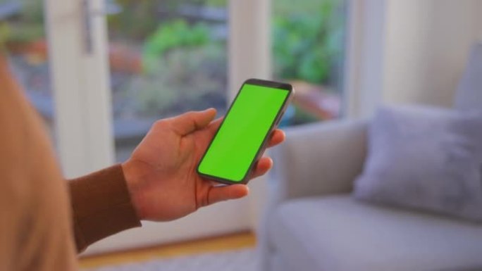 男人在家中的特写镜头，看着智能手机上的空白绿色屏幕-慢动作拍摄