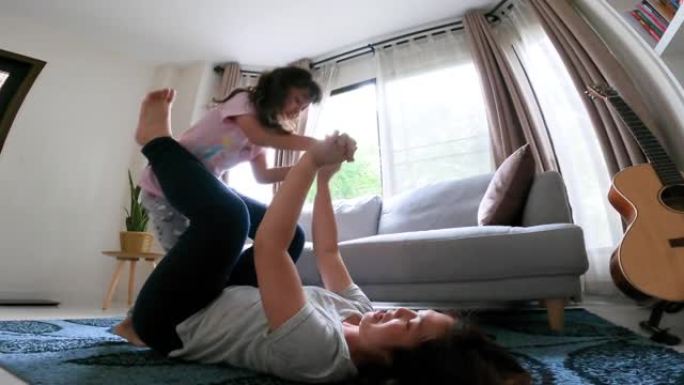 健康的妈妈和女儿在家里的客厅快乐和有趣的玩耍平衡