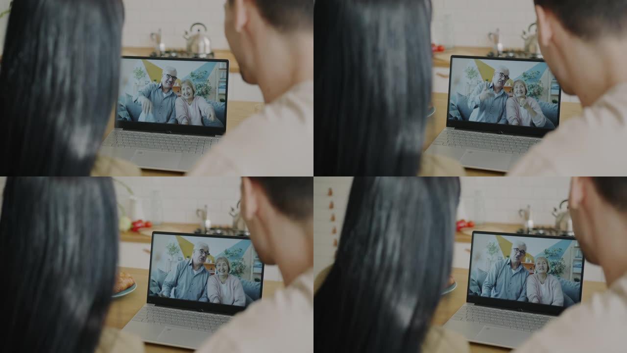幸福的年轻夫妇在家里使用笔记本电脑进行视频通话时与父母老人交谈的肖像