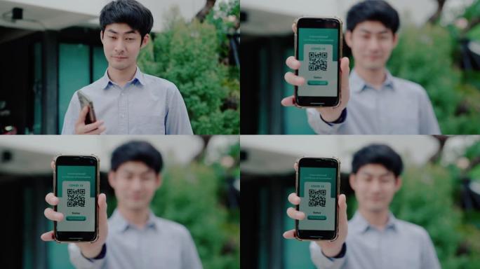 亚洲男子在手机上拿着数字新型冠状病毒肺炎疫苗护照微笑