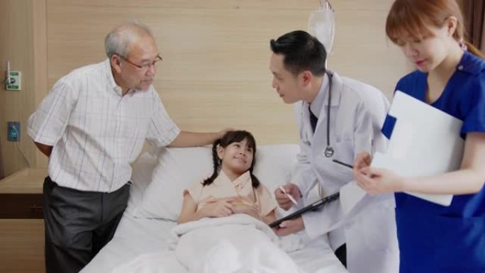 亚洲友好的医生与父母交谈，并在医院病房的平板电脑上显示x射线结果。儿童医院儿科病房。医生随访病情患者