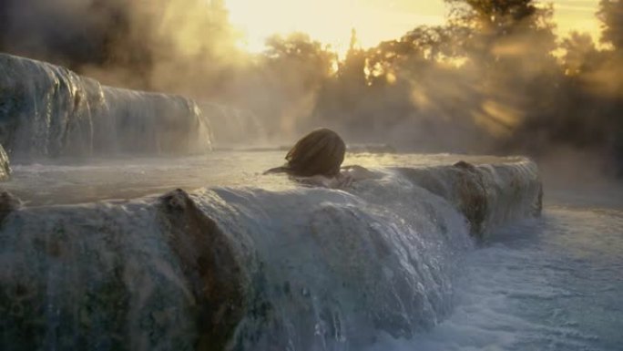 日落时分，SLO MO女人在Saturnia温泉中沐浴