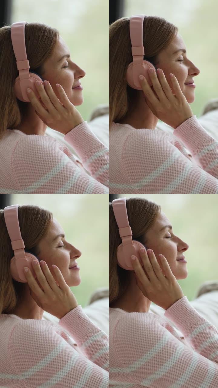 轻松积极冷静的年轻女子调整大粉色无线耳机