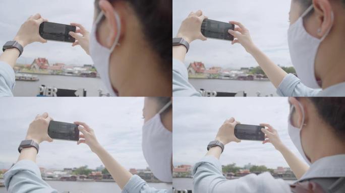 亚洲成年女性在泰国当地旅行时使用智能手机拍照。迷人的女性使用手机摄影，并在当地旅行时发送给她的社交媒