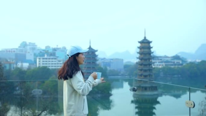 中国桂林市区的年轻妇女喝咖啡并看着宝塔
