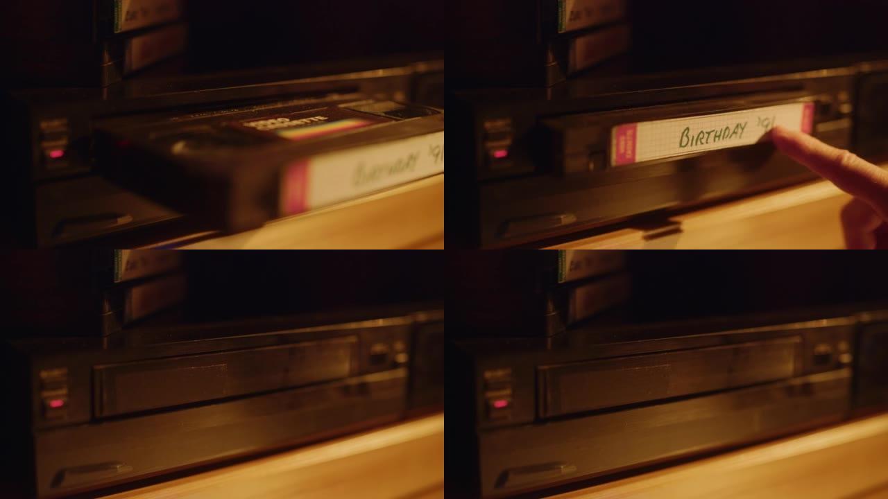 一个人在播放器中插入VHS盒式磁带的特写镜头，并带有家用摄像机的怀旧生日镜头。复古90年代技术概念。