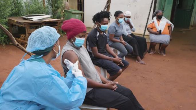 非洲黑人在农村居民点排队接种新冠疫苗。黑人女护士接种疫苗。
