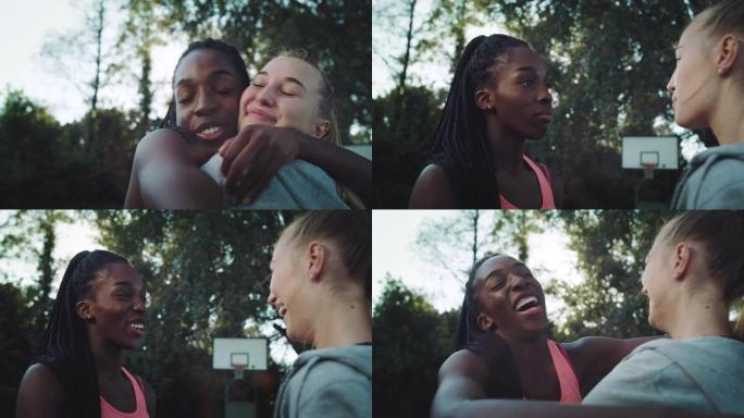 黑人和高加索女孩在篮球场上愉快地见面并拥抱。童年时代的女性朋友在漫长的岁月中团聚并追赶。两个多种族的