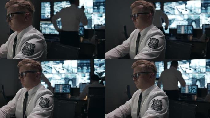 一个穿着白衬衫的短发男子出现在闭路电视监视器的背景上