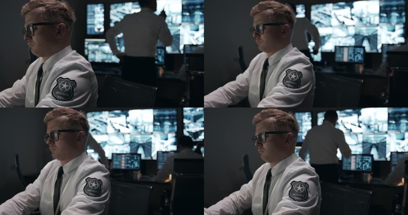 一个穿着白衬衫的短发男子出现在闭路电视监视器的背景上