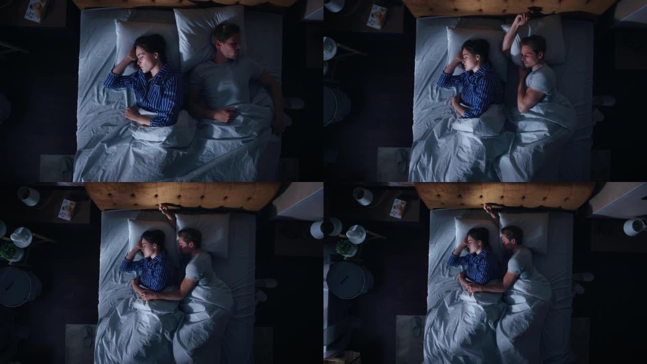 顶视图家: 幸福的年轻夫妇晚上在床上睡觉拥抱在一起。漂亮的女朋友和帅气的男朋友睡在一起。两口之家甜蜜