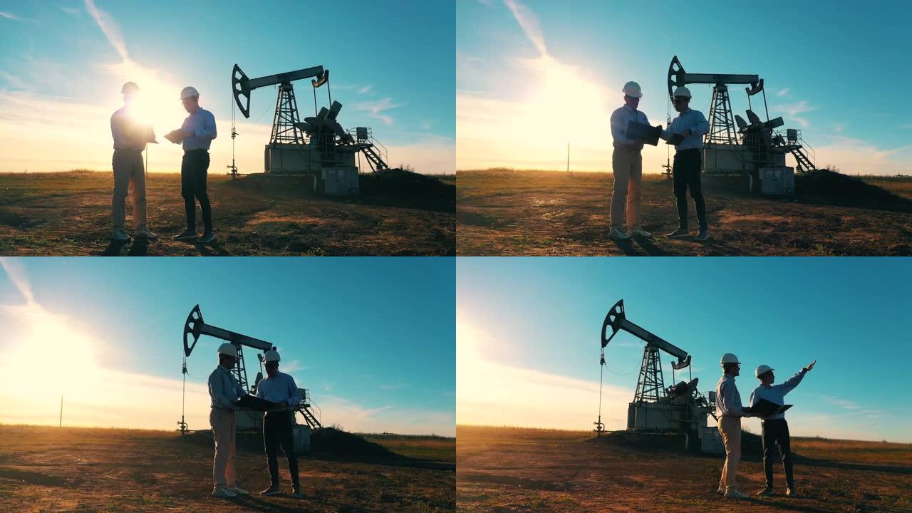 两名石油工人在油田进行讨论