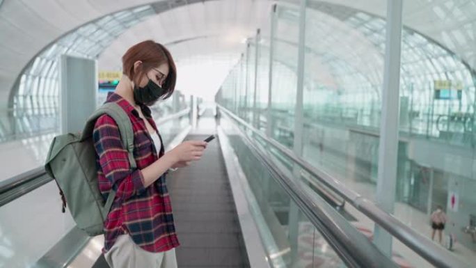 亚洲妇女在机场使用电话戴着防护口罩，新的正常生活方式和旅行理念
