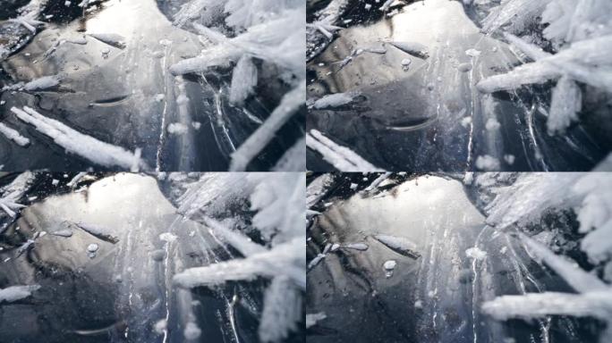 摄像机在冰冻的河流的冰面上缓慢移动。冬季冻水景观。树木和天空反射在冰的镜面上。滑动镜头，4K