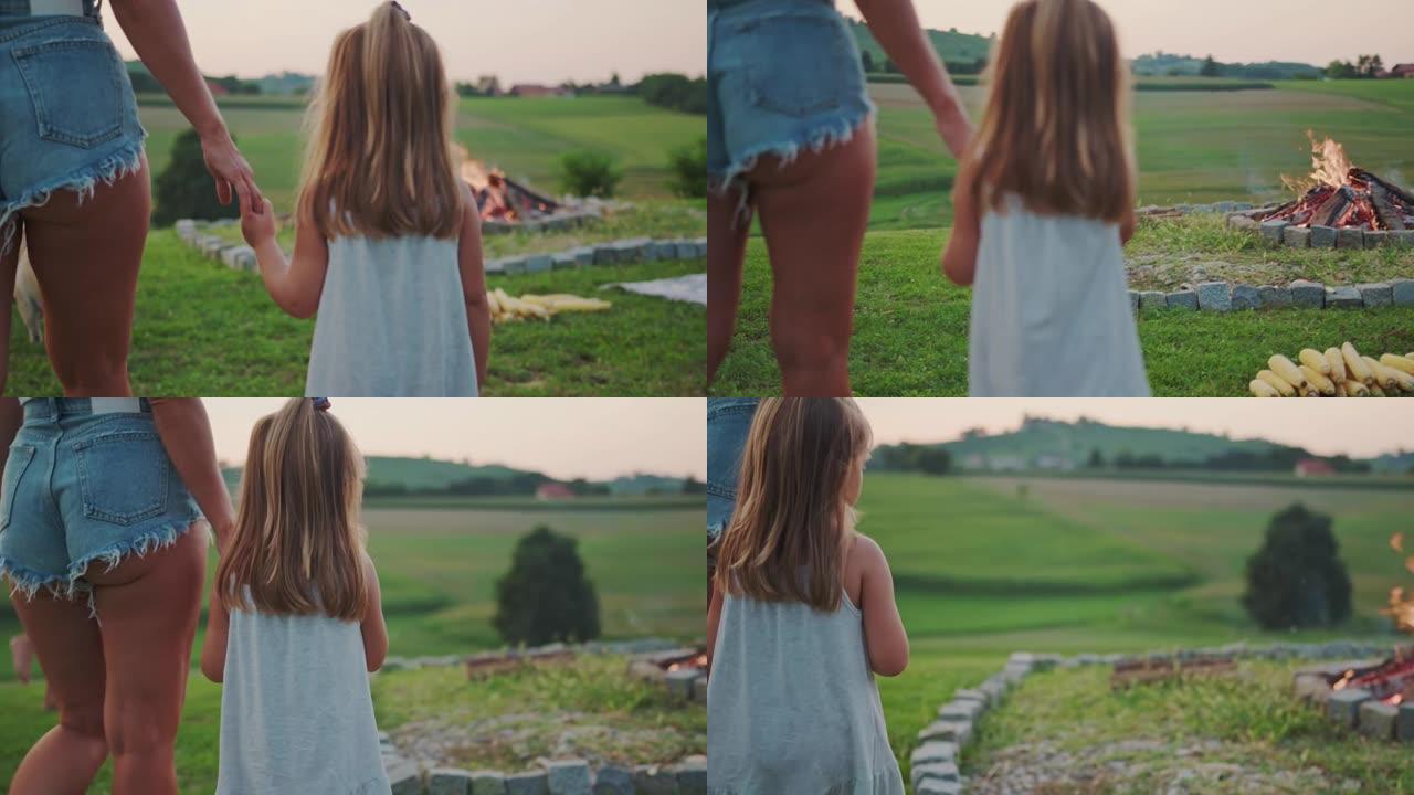 母亲带着小女儿手牵着手走在草地上