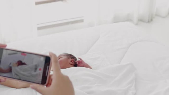 新生婴儿和新手妈妈用智能手机相机微笑着自拍