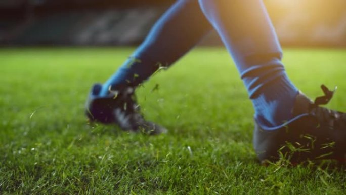 踢足球的靴子腿的特写镜头。职业足球运动员用凶猛的力量击球，进球，草地飞翔。慢动作电影低角度地面艺术镜