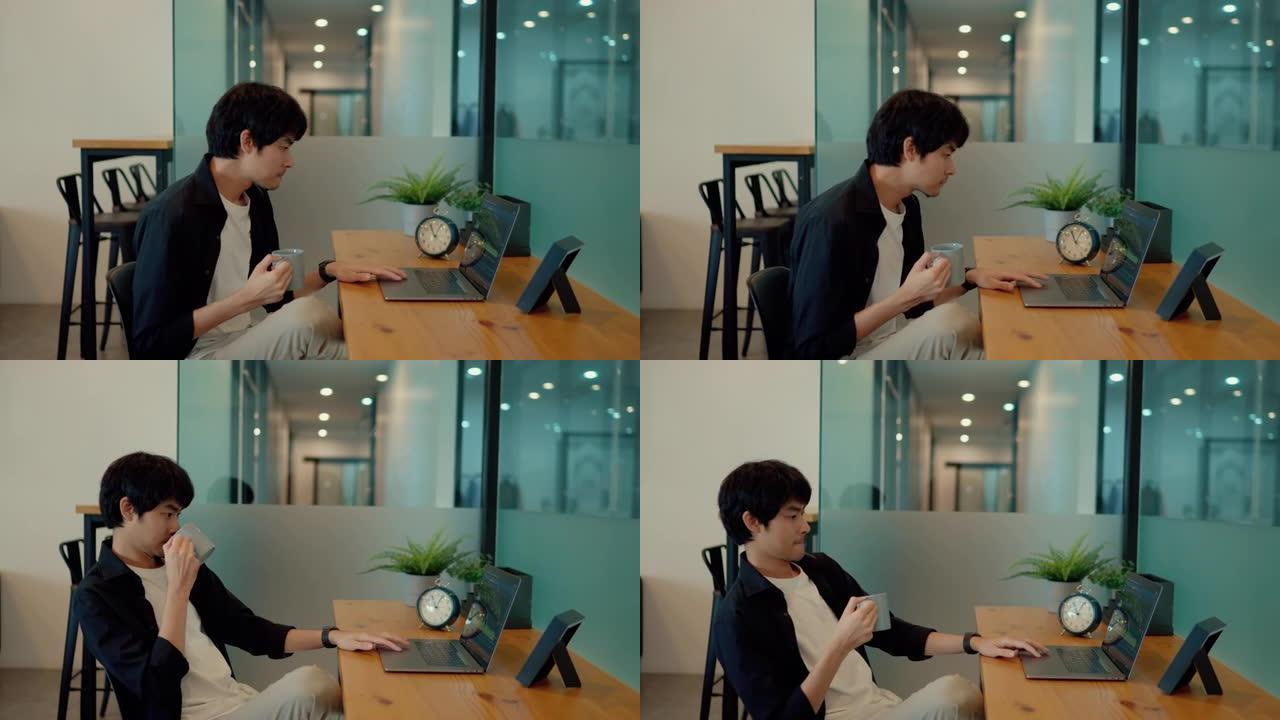 忙碌的亚洲人一边喝咖啡，一边在工作场所的笔记本电脑上看证券交易所。