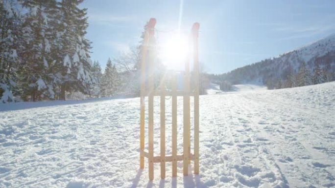 镜头耀斑: 木制雪橇直立在白雪皑皑的草地中间。