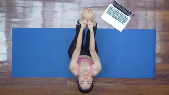 亚洲女性在家用笔记本电脑练习瑜伽的俯视图