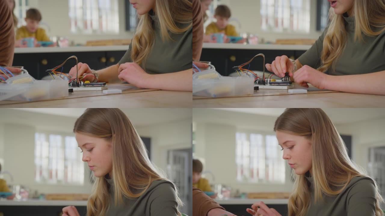 父亲通过电子项目帮助十几岁的女儿坐在家里的厨房桌子上，用慢动作拍摄笔记本电脑