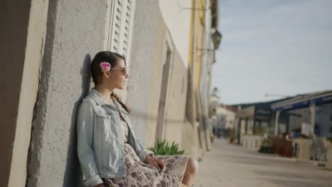 年轻漂亮的女人坐在小巷的石凳上