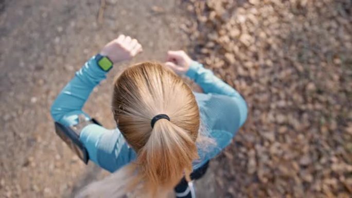 SLO MO女人在土路上慢跑时用色度键屏幕检查她的智能手表