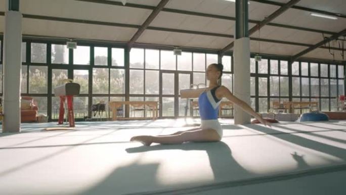 体操运动员女子伸展身体进行表演和练习。年轻，镇定的女运动员用胳膊和腿做体操。在健身房或体育馆训练、杂