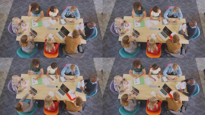 大学或大学生坐在桌子旁与导师坐在一起的头顶镜头