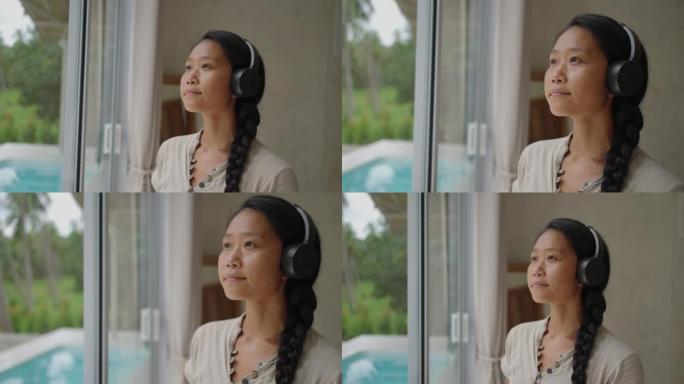 日本女性戴着耳机听音乐时透过窗户看