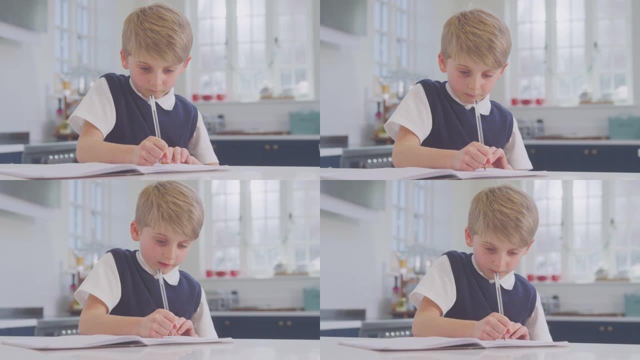 在家穿着校服的男孩在厨房柜台上做作业
