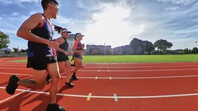侧视亚洲华裔运动员上午在田径场跑步