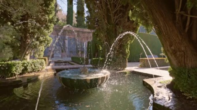 慢动作万向节拍摄的喷泉周围的树木在阿罕布拉的花园Generalife。格拉纳达,西班牙