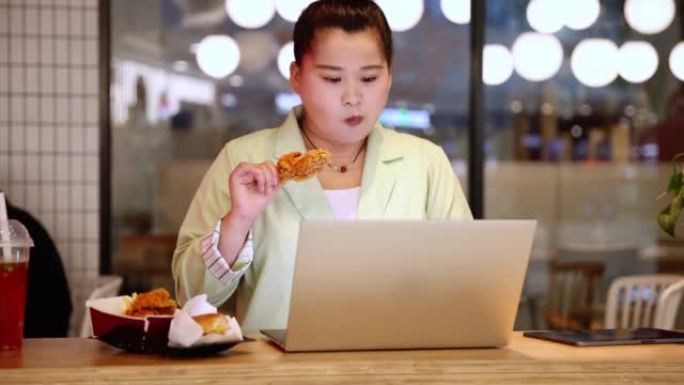 女商人在使用笔记本电脑时吃炸鸡